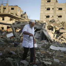 Un uomo cammina sulla macerie di alcuni edifici distrutti dai bombardamenti israeliani su Gaza (Reuters)