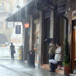 Persone si riparano dalla piogga a Bologna dove il maltempo ha portato abbondandti precipitazioni (Ansa)
