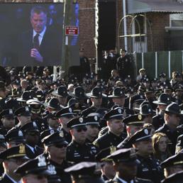 Gli agenti di polizia newyorchesi voltano le spalle al megaschermo durante il discorso del sindaco de Blasio (Reuters)