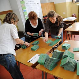 Scrutatori preparano le schede in un seggio elettorale di Milano per il voto amministrativo del 15 e 16 maggio (Ansa)