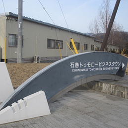 Ricostruzione lenta e occasioni perdute. Nella foto l'ingresso di quella che doveva essere la nuova "business town" in cui la città di Ishinomaki pensava di attrarre investimenti dall'anno scorso: sullo sfondo i prefabbricati (sono quasi 1.200) sorti al posto delle fabbriche, a causa dello tsunami, per ospitare 2.500 sfollati