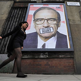 Una donna passa davanti a un manifesto di Rupert Murdoch, con un adesivo che dice "What a Jeremy Hunt" riferendosi al ministro della Cultura Jeremy Hunt, a Central Street, Islington, Londra (Epa)