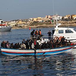 Migranti sbarcano nel porto di Lampedusa (Ansa)