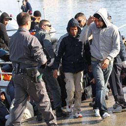 Migranti sbarcano nel porto di Lampedusa. Marzo 27, 2011 (ANSA/FILIPPO VENEZIA)