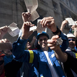 Operai dell'Alcoa strappano le tessere elettorali durante la manifestazione sotto il ministero dello Sviluppo Economico a Roma (Ansa)
