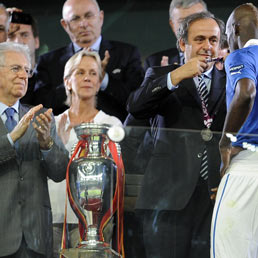 Il presidente Michel Platini con Mario Balotelli, mentre il premier italiano Mario Monti lo applaude durante la cerimonia di premiazione di Uefa Euro 2012 (Ansa)