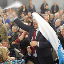 Il contestatore di Berlusconi mentre lancia sul palco aeroplanini di carta (Ansa)