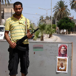 Un posto di blocco con la foto di Gheddafi e lo slogan "vivo o morto"