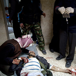 In Siria il bilancio della repressione  di oltre 8.000 morti. Nella foto alcuni uomini prestano soccorso a un ribelle ferito a Idlib (AP Photo)
