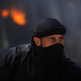 Nella foto un combattente del gruppo siriano islamico ribelle Jabhat al-Nusra davanti fronte ad un veicolo in fiamme (Reuters)