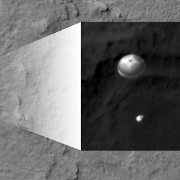 La capsula che contiene il rover marziano Curiosity sta arrivando sul suolo del pianta frenata dal più grande paracadute supersonico mai costruito. L'immagine presa dalla sonda NASA Mars Reconnaissance Orbiter, dotata di una eccezionale camera fotografica, HiRise.